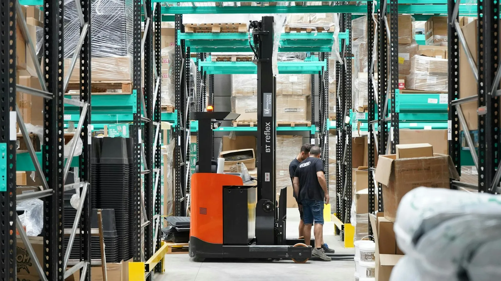 Depo raflarının önünde forklift ve çalışan (temsili görsel)